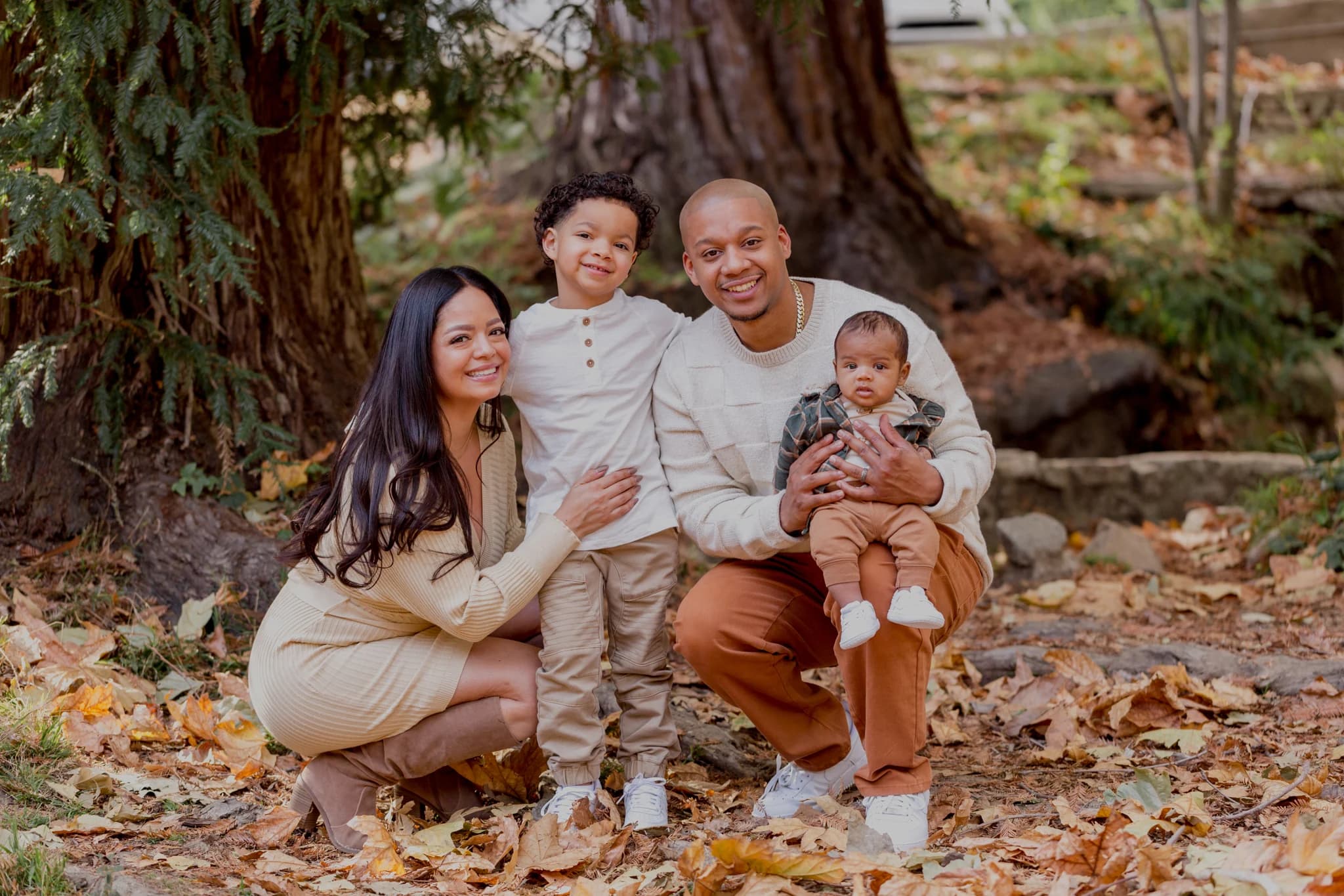 A family laughing together beneath trees in autumn