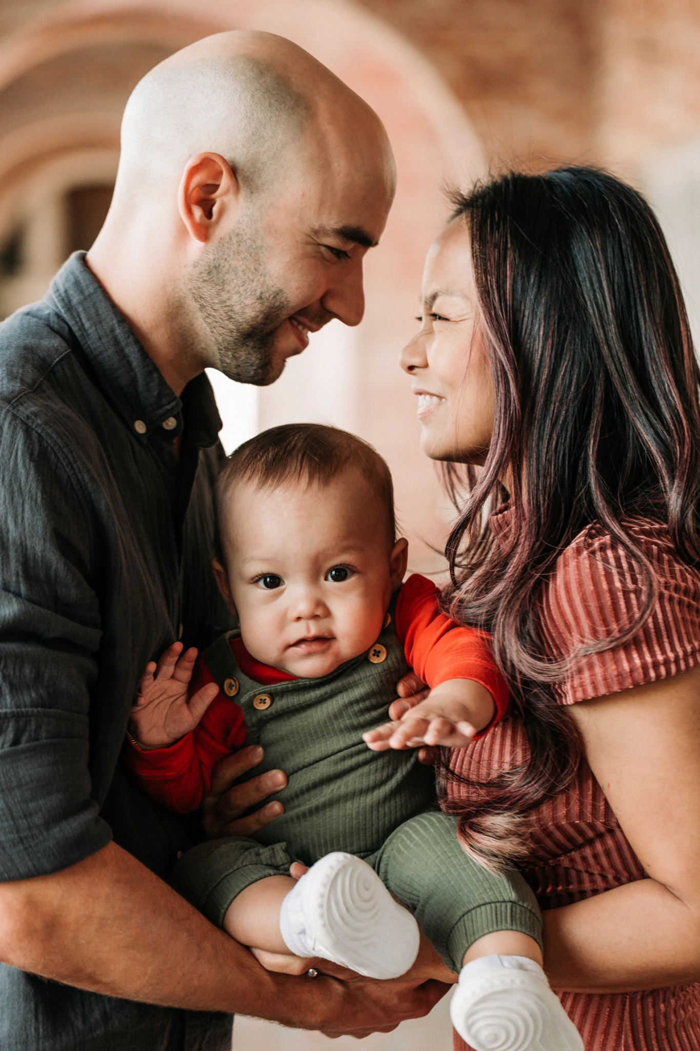 Parents holding their baby close beneath a brick arch