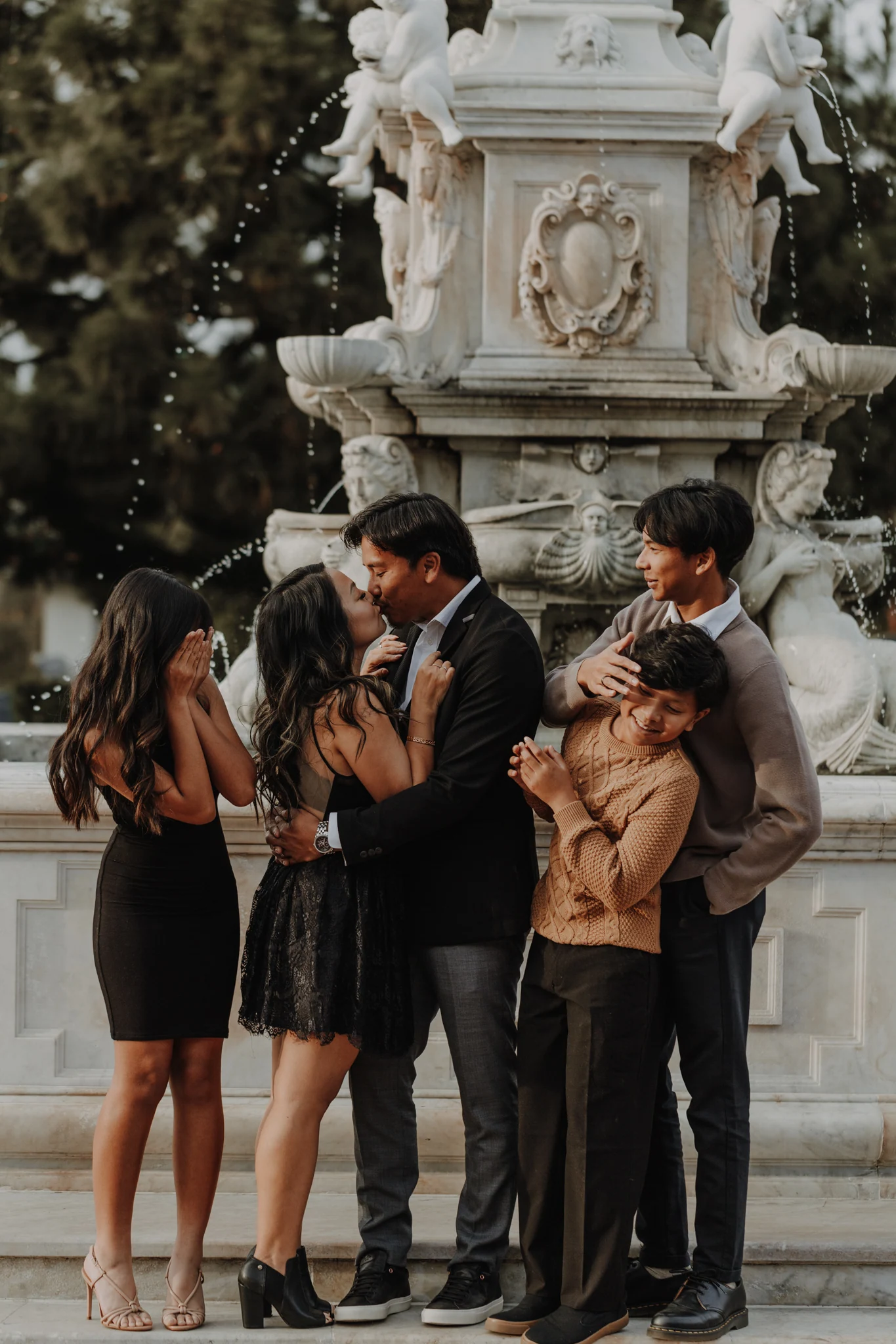 A family sharing a laugh together beside a stone fountain
